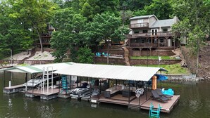 Una propiedad frente al lago con muelle, zona de estar cubierta y una casa con balcón.