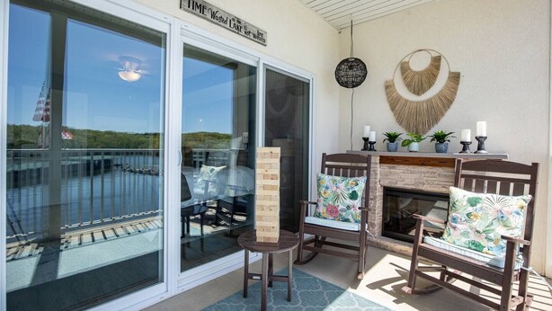 A patio with a glass door, a fireplace, and two chairs with floral cushions. - WaterFront Getaway Parkview Bay! Lux Condo 3Pools! (Osage Beach)