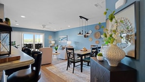A modern kitchen with a dining area, featuring a large island, pendant lights, and decorative wall art. - WaterFront Getaway Parkview Bay! Lux Condo 3Pools! (Osage Beach)