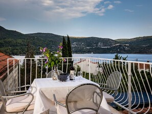 A terrace with a table set for two, overlooking a lake with hills in the background. - Apartments and Room Eva Slano - One Bedroom Apartment With Terrace and Sea View (Dubrovacko Primorje)