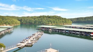 A lakeside dock with multiple boat slips and covered areas, surrounded by dense forest.