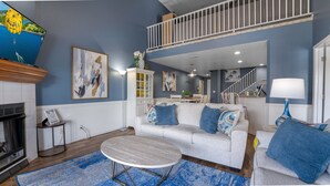 A living room with a white sofa, blue cushions, a round coffee table, and a blue rug.
