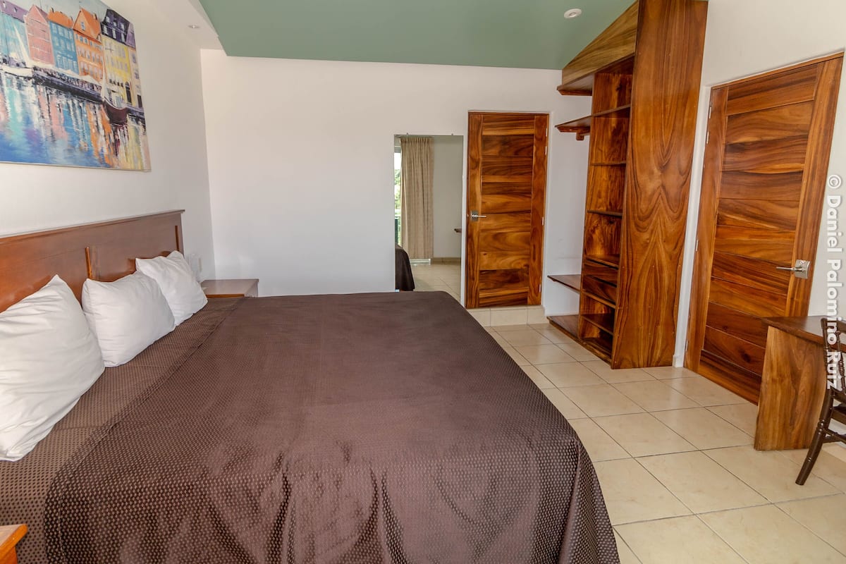 Un dormitorio con una cama grande, un armario de madera y un cuadro en la pared.