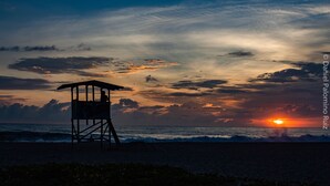 Ein Rettungsturm an einem Strand bei Sonnenuntergang.