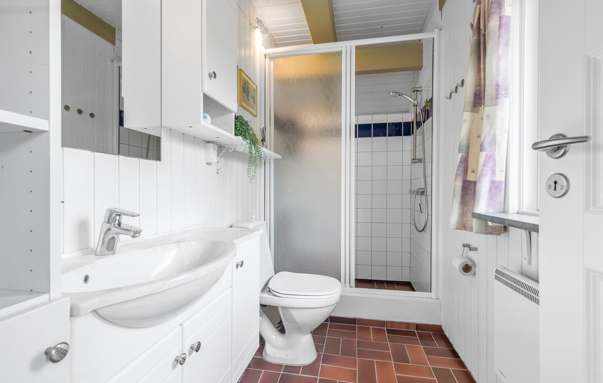 A bathroom with a white sink, toilet, and shower area.