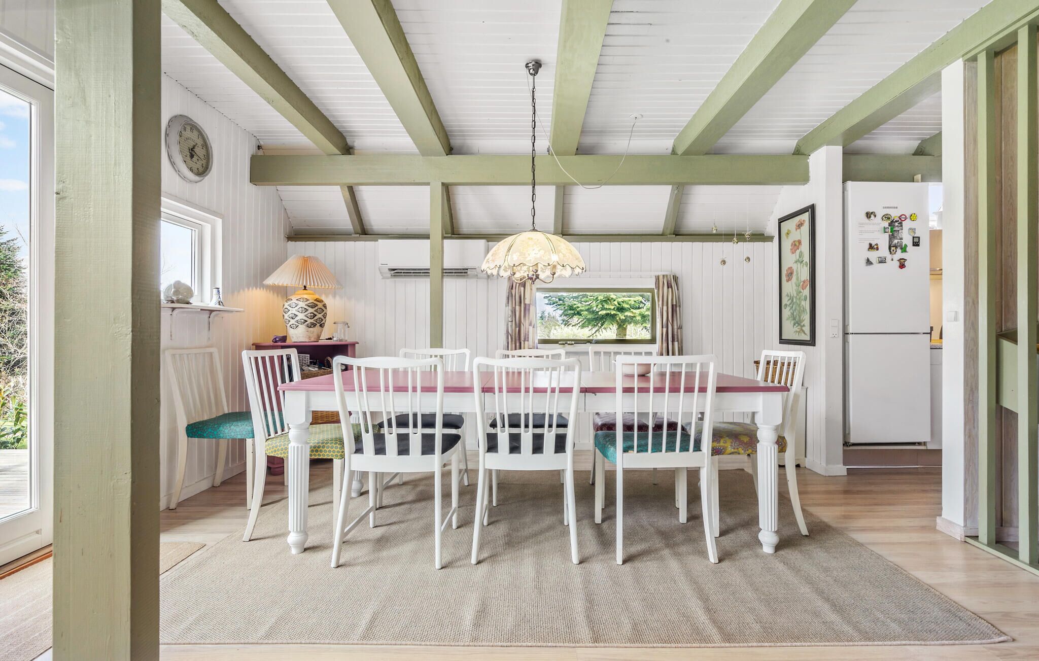 Un comedor con una mesa de madera, sillas blancas y una lámpara colgante.