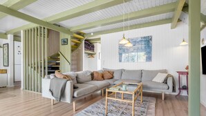 Ein modernes Wohnzimmer mit einem Ecksofa, einem Couchtisch und einer Treppe mit grünen Akzenten.