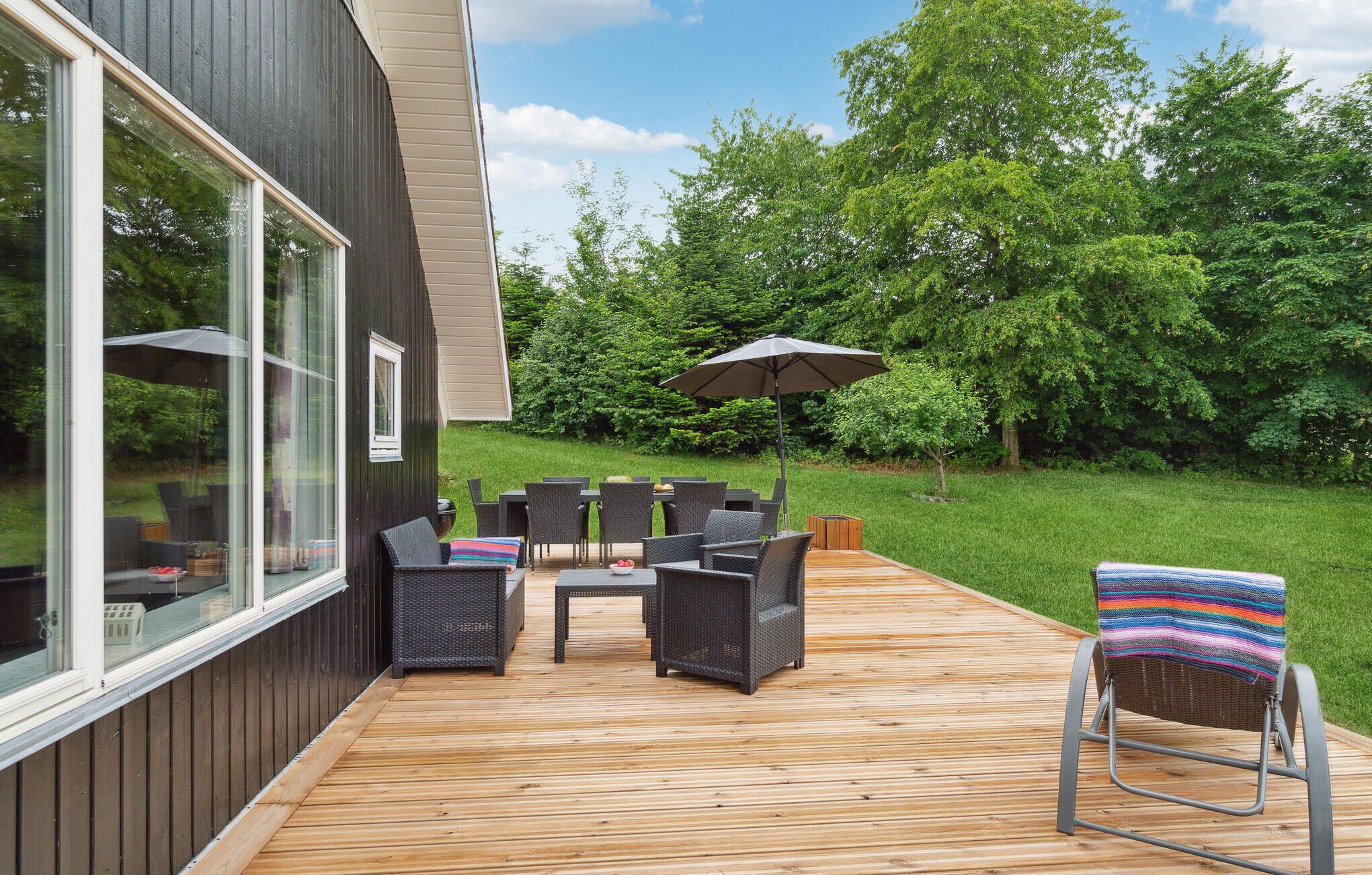 A deck with outdoor furniture, a table, and an umbrella.