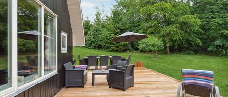 A deck with outdoor furniture, a table, and an umbrella.