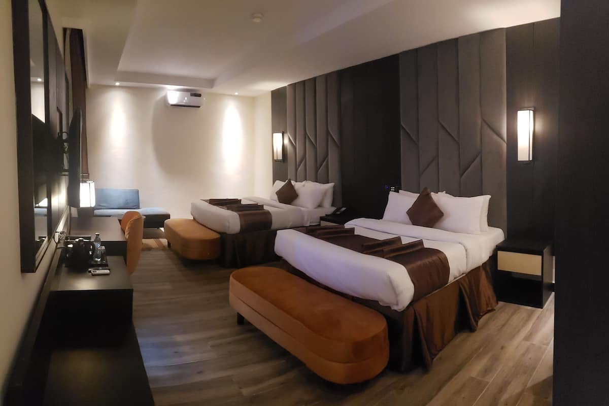 Ein modernes Hotelzimmer mit zwei Betten, einem Schreibtisch und einer Sitzecke.