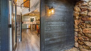 A modern kitchen with a stone wall and a wooden door.