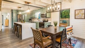 A spacious kitchen with a central island, wooden bar stools, and pendant lighting.