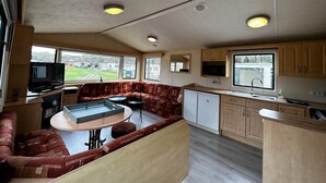 Eine kompakte Wohnmobilküche mit Essbereich, integriertem Fernseher und einer Küchenzeile.