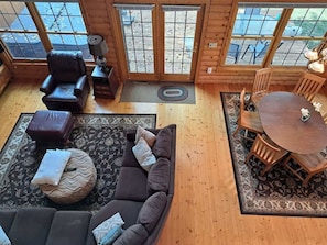 A cozy interior with a sectional sofa, a dining table with chairs, and a large window with a view of the outdoors.
