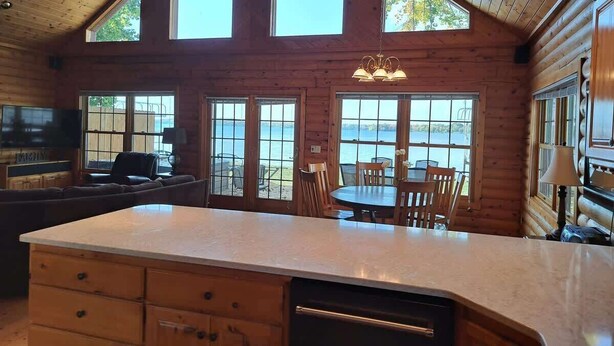 A cabin with a kitchen, dining area, and large windows overlooking a body of water. - Tradewinds on Cormorant, Audubon, MN (Audubon)