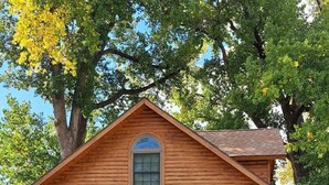 A wooden cabin with a porch, a door, and a window. - Tradewinds on Cormorant, Audubon, MN (Audubon)