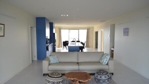 A modern living room with a sofa, coffee table, and patterned ottomans.