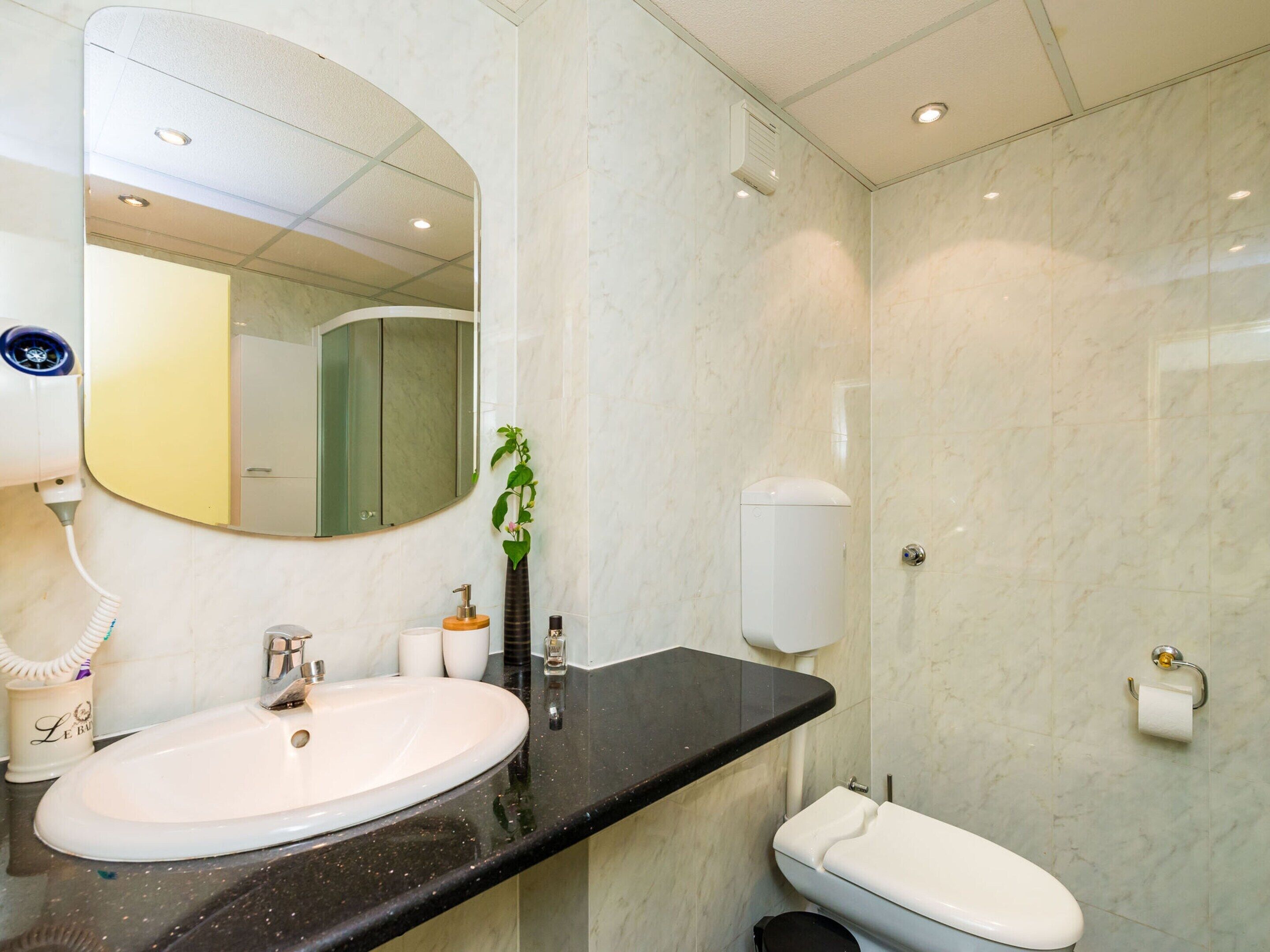 Ein modernes Badezimmer mit einem weißen Waschbecken, einer schwarzen Arbeitsplatte und einer weißen Toilette.