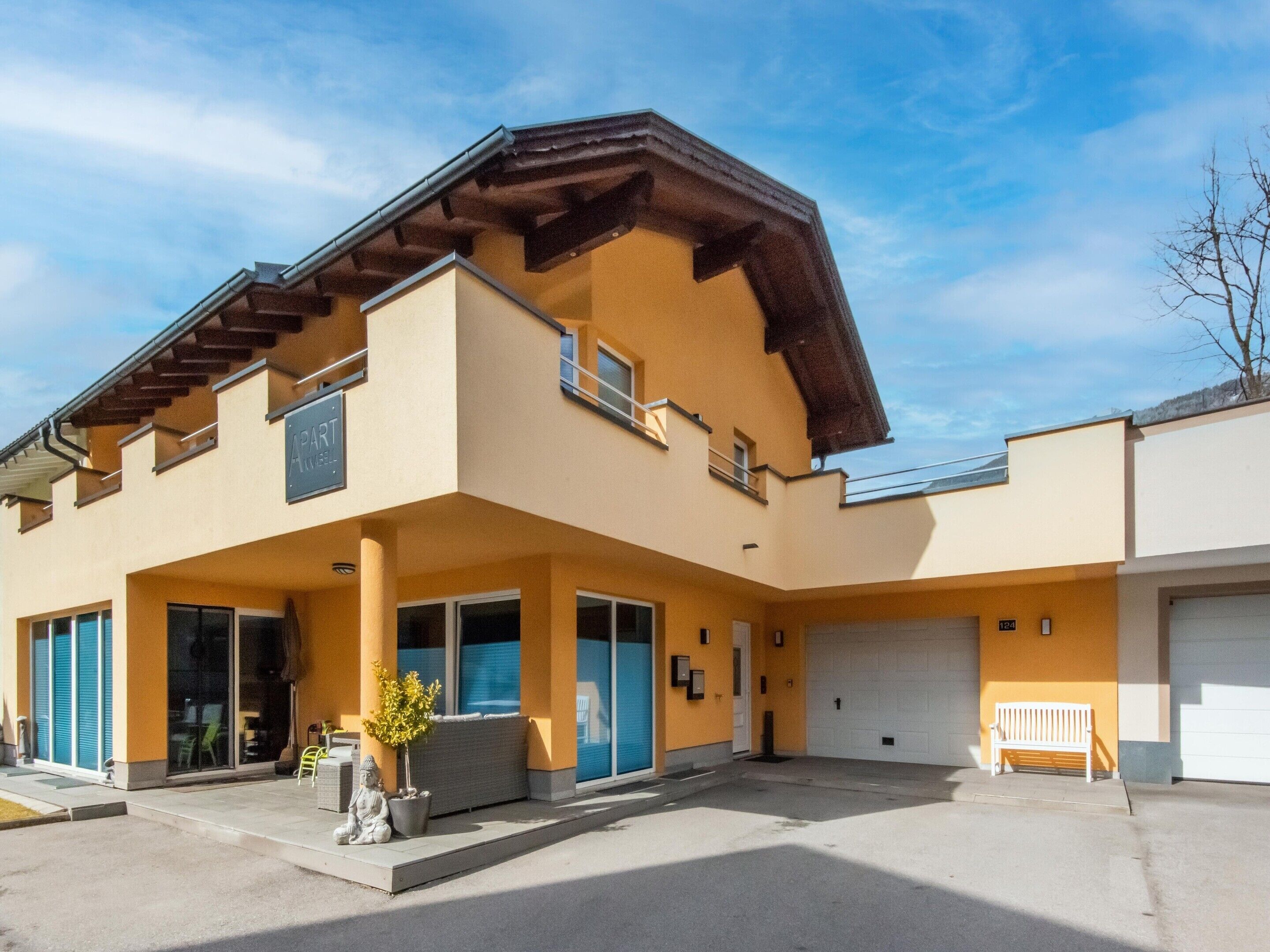 Il s’agit d’un immeuble à deux étages, doté d’un toit plat et d’un balcon à l’étage supérieur. Une porte de garage se trouve sur le côté droit du bâtiment.