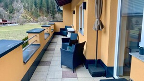 An outdoor patio with seating, a covered area, and a view of a forested area. - Modern Apartment in the Otztal (Oetz)