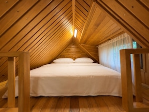 A bedroom with a wooden sloped ceiling, a bed with white bedding, and a window with sheer curtains. - Uzungol Cerrahpasa Suites (Çaykara)
