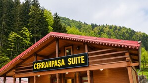 A wooden cabin with a sign reading 'CERRAHPASA SUITE' and a balcony with tables and chairs. - Uzungol Cerrahpasa Suites (Çaykara)