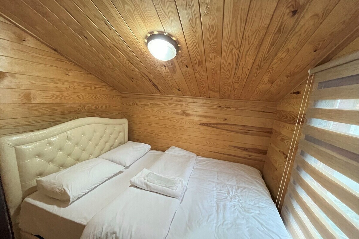A wooden-paneled room with a bed, a headboard, and a ceiling light.