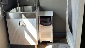 Una cocina compacta con pileta, alacenas y un pequeño armario.