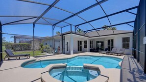 A pool with a hot tub, sun loungers, and a covered patio area. - Remodeled Golf Course Pool & Spa Home (Davenport)
