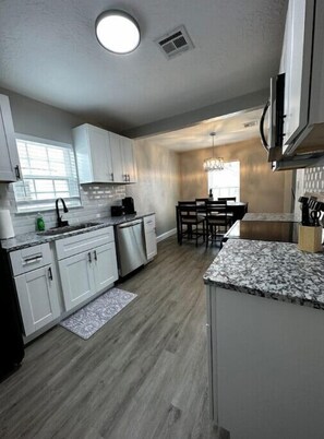 Enjoy meals in this kitchen with dishwasher, sink, and dining area with table and chairs.