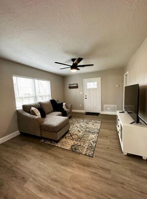 Relax in this inviting living room with a sofa, patterned rug, and television.