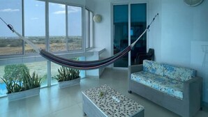 Amplia sala de estar con una hamaca, un sofá y una mesa de centro.