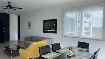 Ein modernes Wohnzimmer mit einem Glastisch, einer Couch und einem Esstisch für sechs Personen.