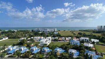 Uma área de resort costeira com vários edifícios, alguns com telhados azuis, e vista para o oceano.