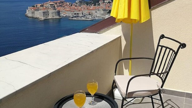 A balcony with a table and chairs, overlooking a coastal cityscape. - Apartments Horizon - Double Room With Balcony and Sea View (Dubrovnik)