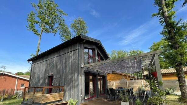 Une cabane en bois rustique dotée d’une terrasse, de meubles d’extérieur et de plantes en pot.