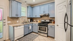 A kitchen with light blue cabinets, a stainless steel refrigerator, a gas stove, and a dishwasher. - Spacious 6-bedroom Duplex  w/Pool Mins FC Stadium / Domain (Austin)
