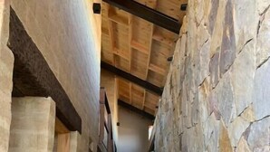 A narrow hallway with stone walls and wooden beams, leading to a door at the end. - Casa Pionono (Guasca)