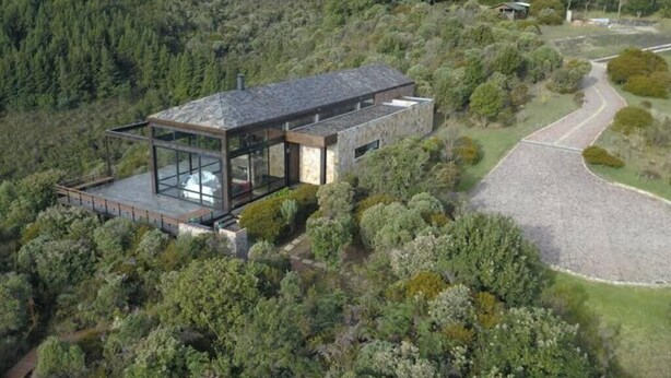 A modern house with a glass extension, surrounded by dense forest. - Casa Pionono (Guasca)
