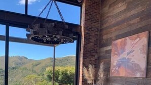 A dining area with a glass table and chairs, a hanging light fixture, a brick wall, and a painting. - Casa Pionono (Guasca)
