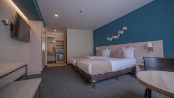 Habitación de hotel con una cama grande, un escritorio, una silla y un televisor.
