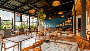 A modern cafe with wooden furniture, a blue wall with decorative plates, and large windows offering city views. - Hotel Faranda Collection Zona G (Bogotá)