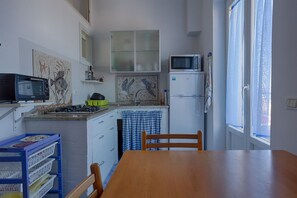 A compact kitchen with a microwave, refrigerator, and a dining table with chairs.