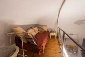 A small room with a bed, a side table, a radiator, and a window.