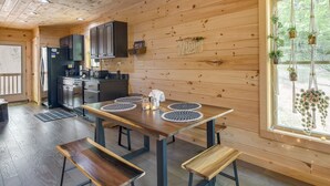Un intérieur en bois comprenant une cuisine, une table à manger avec des bancs et une fenêtre agrémentée de plantes.