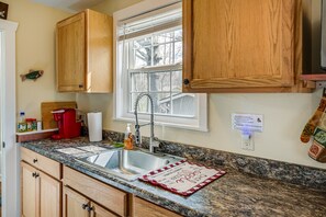 A kitchen with wooden cabinets, a granite countertop, a stainless steel sink, and a window above the sink.