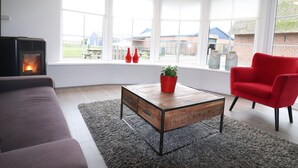 A modern living room with a sofa, a red chair, a wooden coffee table, and a fireplace.