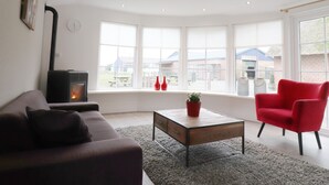 A living room with a sofa, a red chair, a coffee table, and a fireplace.
