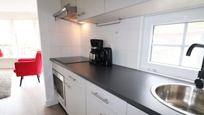 A modern kitchen with white cabinets, a black countertop, a stainless steel sink, and a coffee maker.