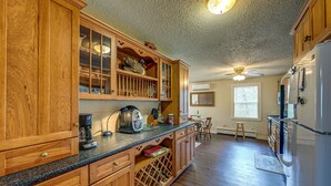 A kitchen with wooden cabinets, a countertop with a coffee maker, and a refrigerator. - Private Hot Tub & Covered Deck: Cozy Whittier Gem (Whittier)